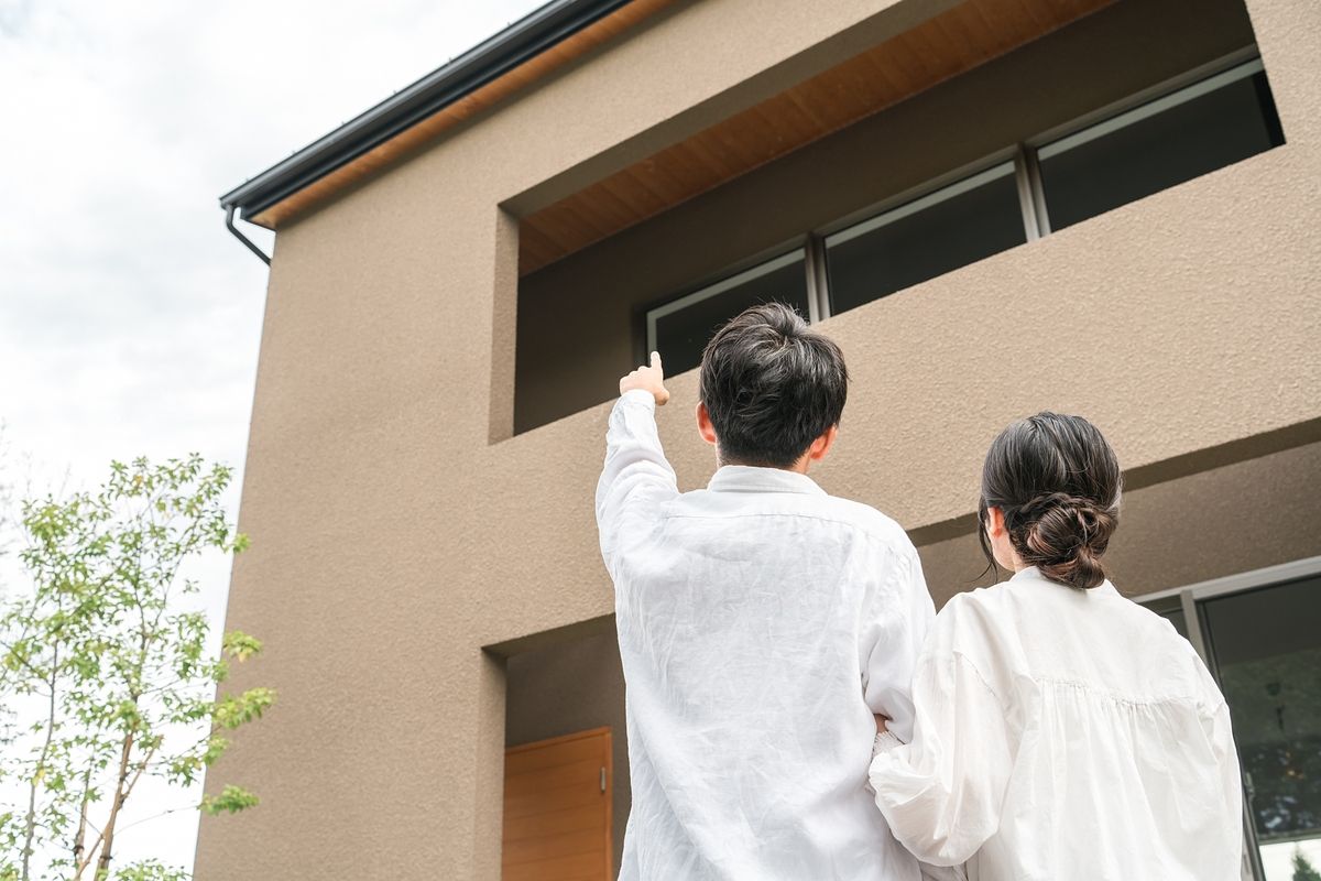 不動産の新築物件を指さす夫婦